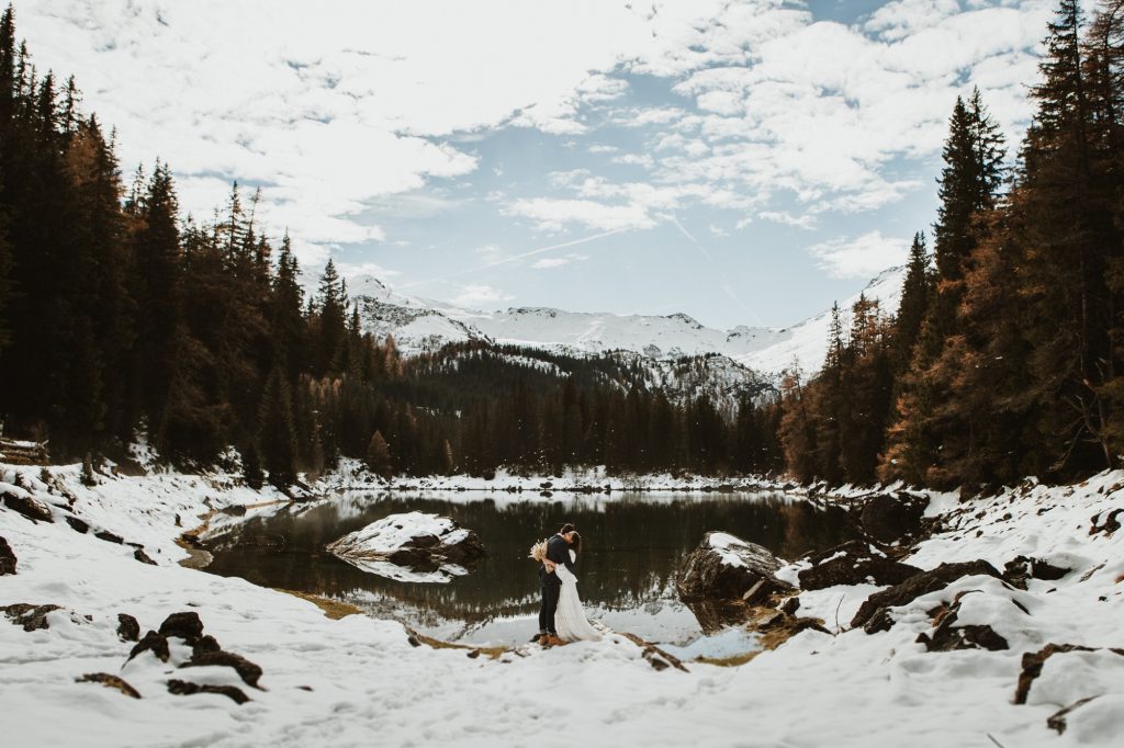 Couple hugging by a lake in snowy mountains