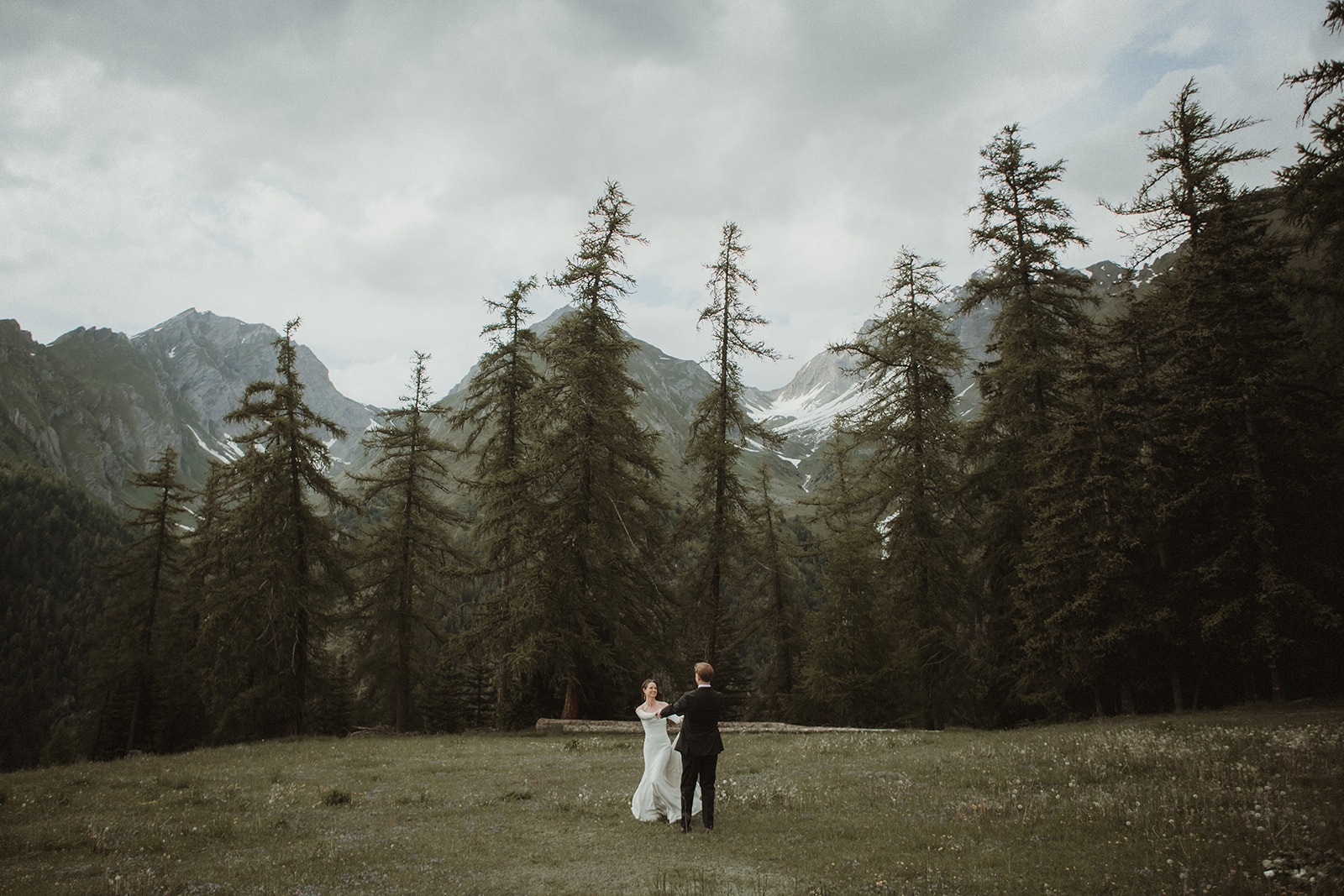 Couple dancing after exchanging their vows on a flowery meadow in the Italian Alps