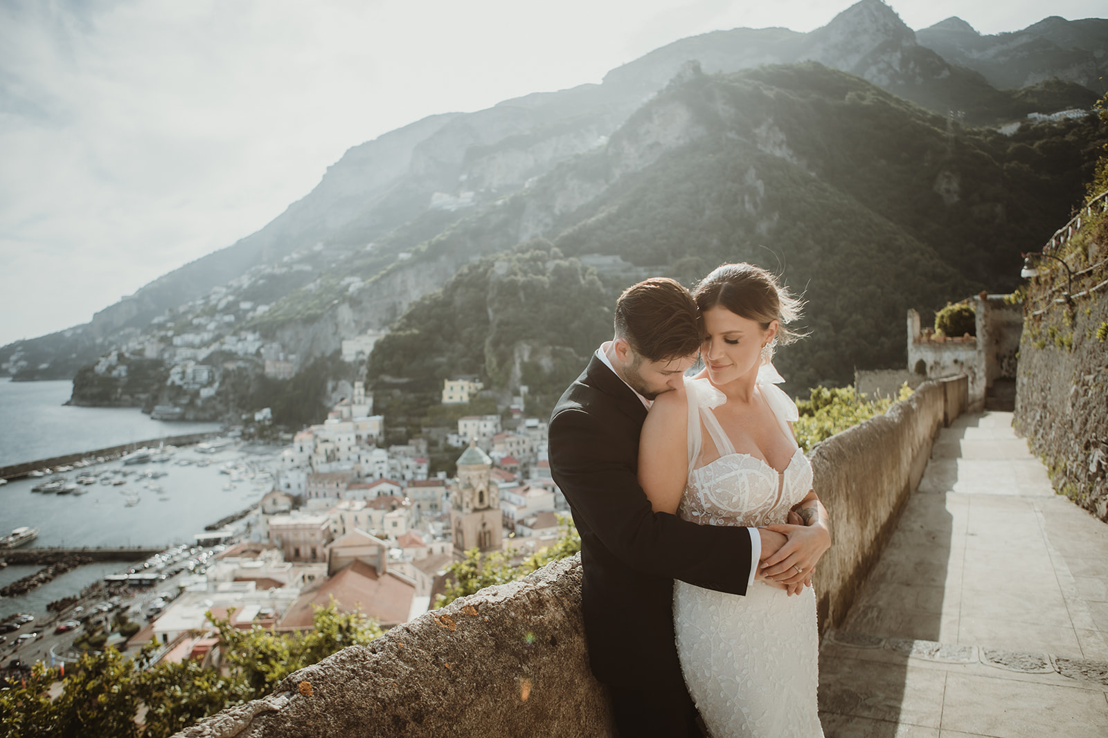 Couple embracing at sunset with dramatic view of Amalfi in the background during their elopement in Italy