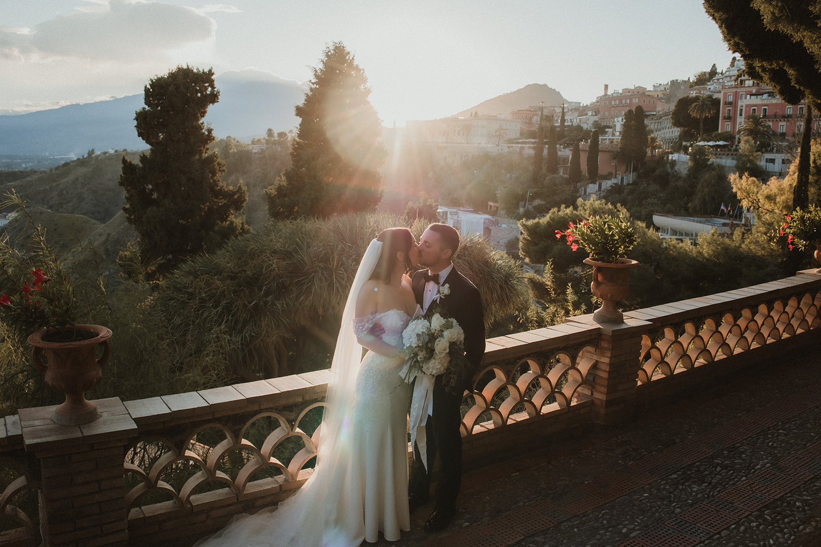 Couple kissing at sunset with dramatic light and view of Taormina on their elopement in Sicily