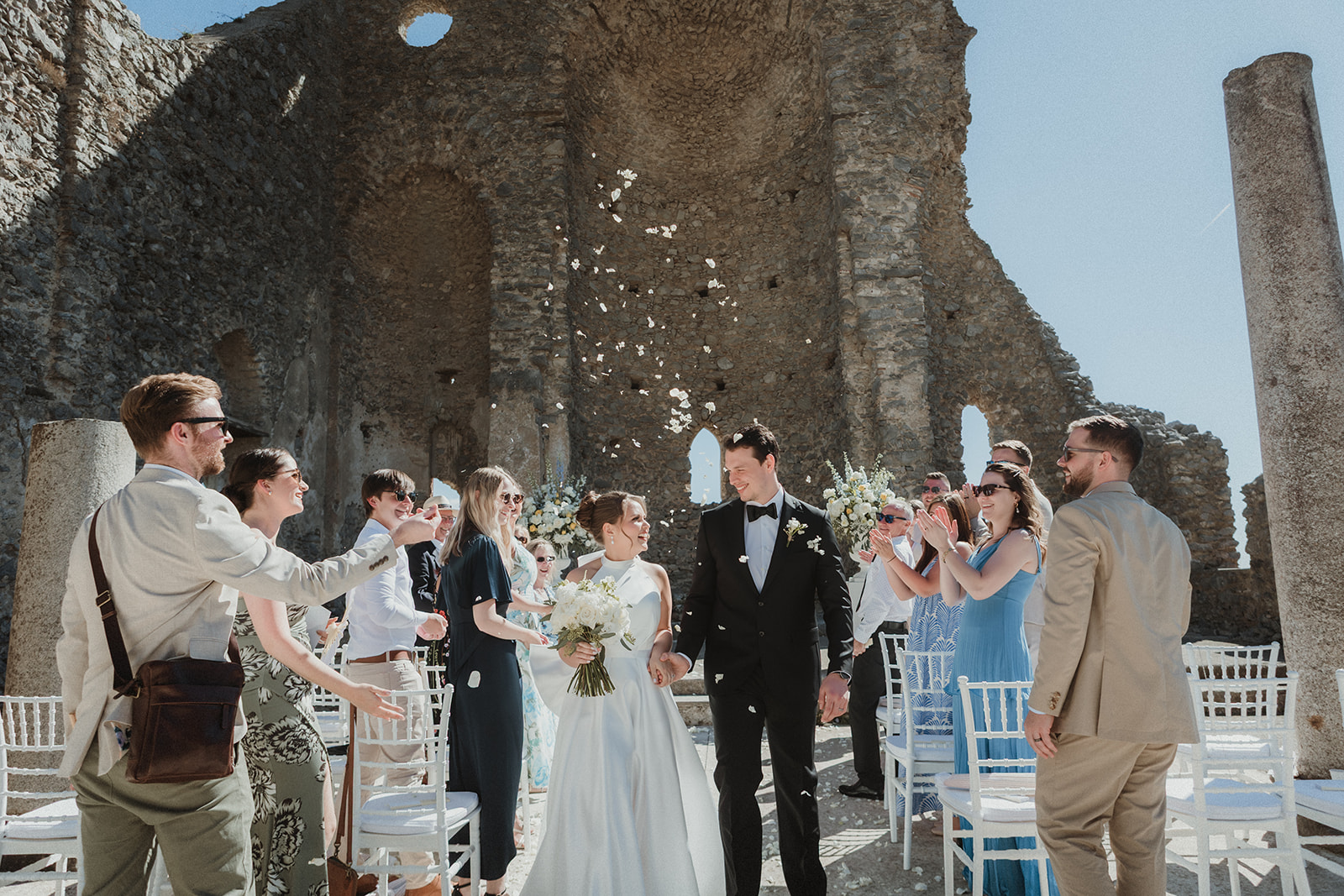 Couple laughing while small wedding party throws confetti after their ceremony for their elopement in the Amalfi Coast