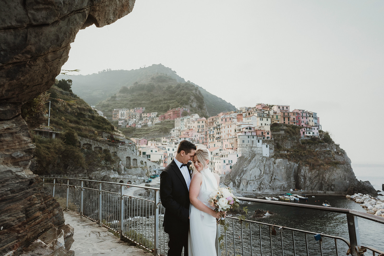 Couple embracing at sunrise with views on Manarola in the background for their elopement in Cinque Terre