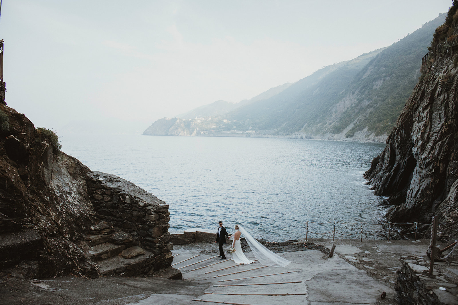Adventure couple exploring the Ligurian Cliffside coast on their sunrise elopement in Italy