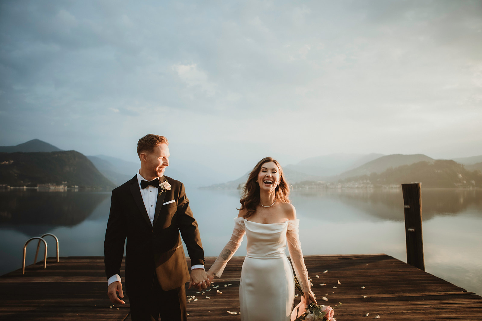 Couple laughing right after exchanging vows at dawn in the most intimate lakeside setting for their elopement in Italy
