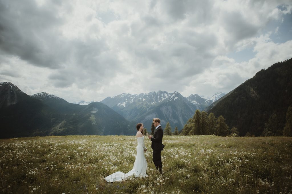 Couple exchanging vows in a secluded alpine meadow with 360-degree mountain views in the Aosta Valley, Italy.