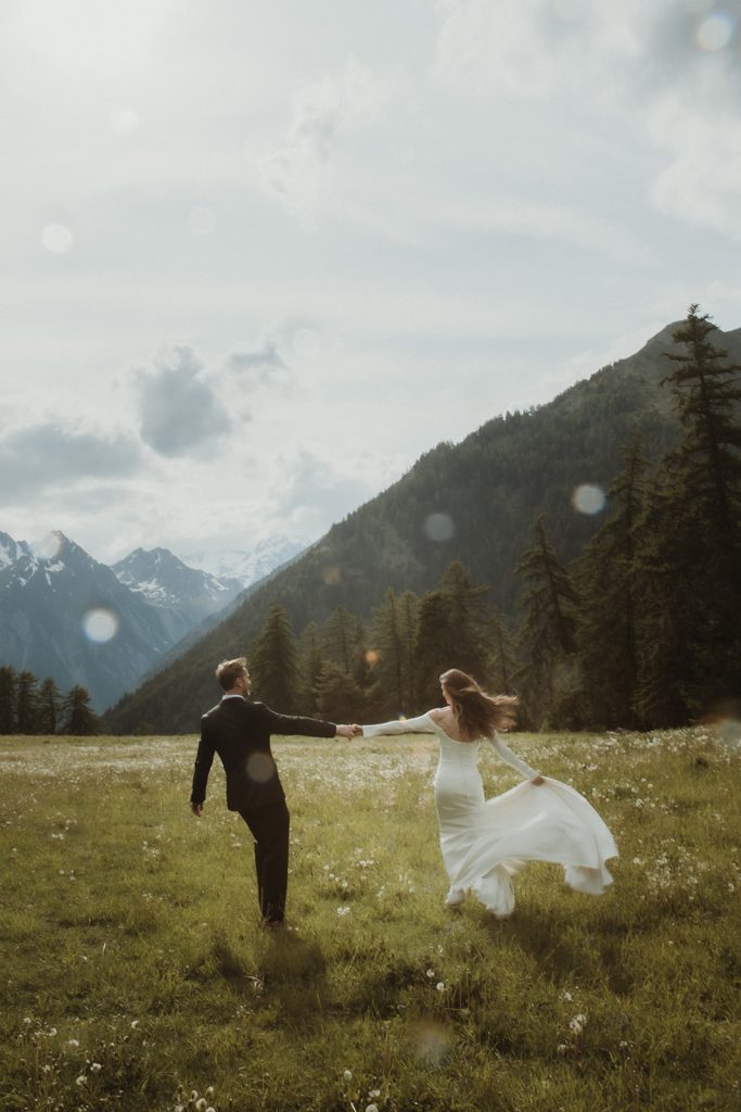Couple dancing in the rain in an alpine field during their intimate mountain elopement in Italy.