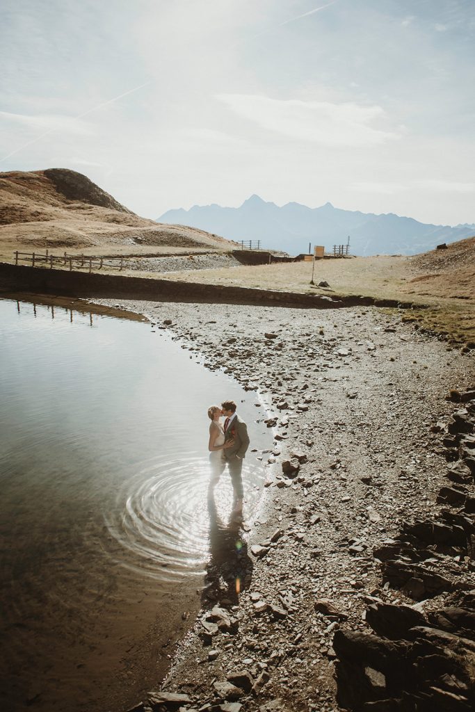 Adventure elopement Italy: couple photographed by a secluded lake in the Aosta Valley, Italian Alp