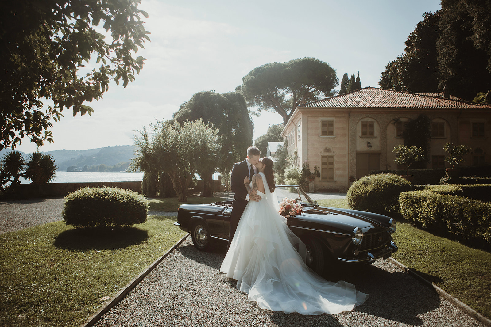 Couple portrait shots with an Italian vintage car in a luxury villa on Lake Como they rented for their elopement in Italy