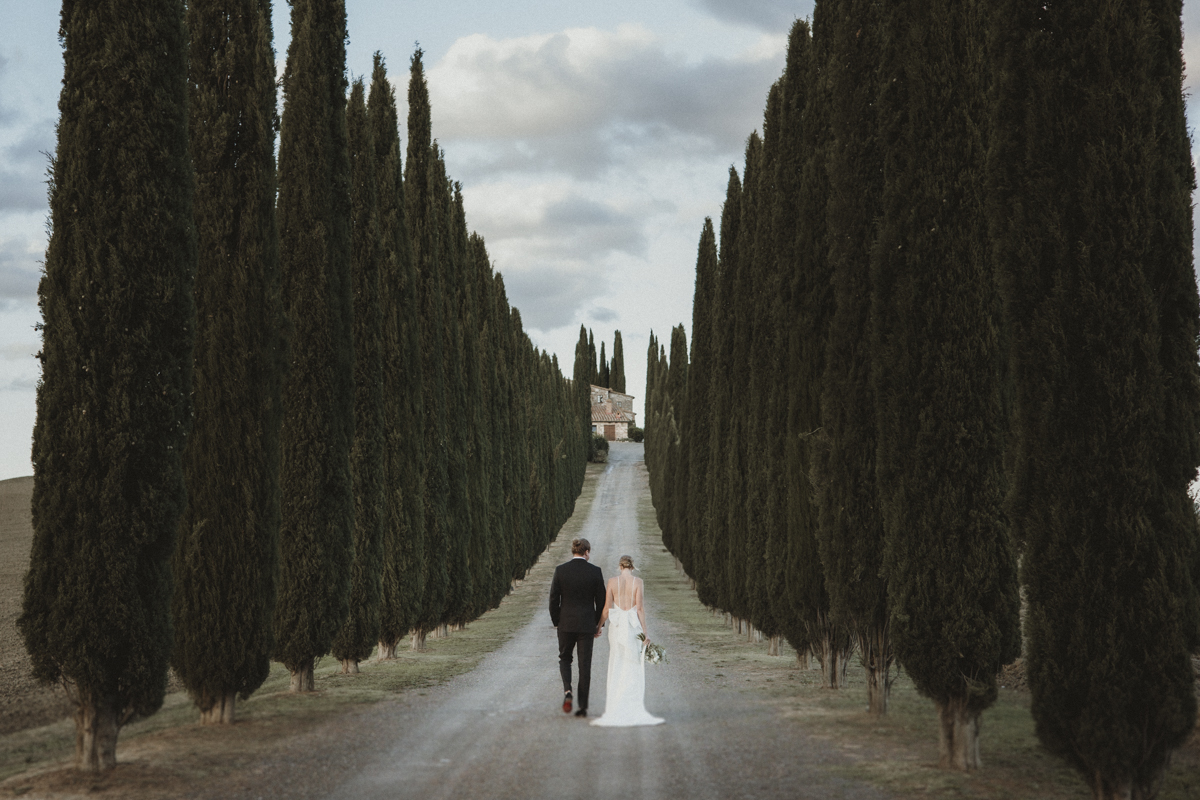 Couple walking through a Tuscan lane with cypresses on their elopement in Italy