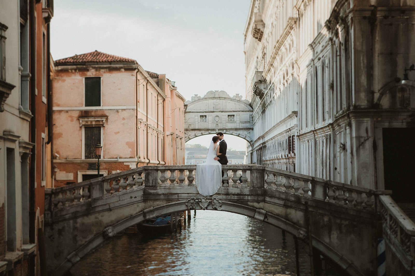 Couple having an intimate moment on a Venice bridge with Ponte dei Sospiri in the background on their elopement in Venice