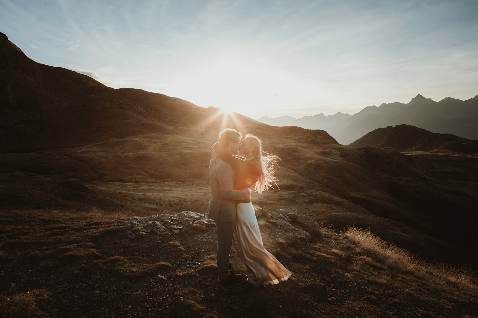 Couple kissing as the sun rises on a spectacular mountain view during their elopement in the Italian Alps