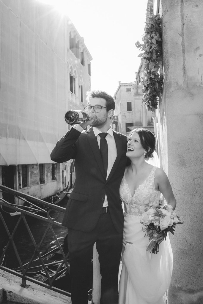 Fun picture of a couple with a bottle of Champagne happily celebrating their elopement in Venice