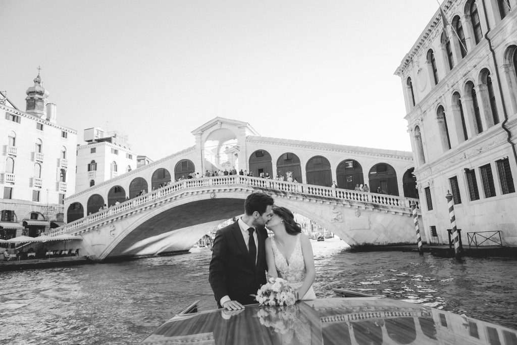 Couple kissing in front of Ponte di Rialto on their boat tour during their elopement in Venice