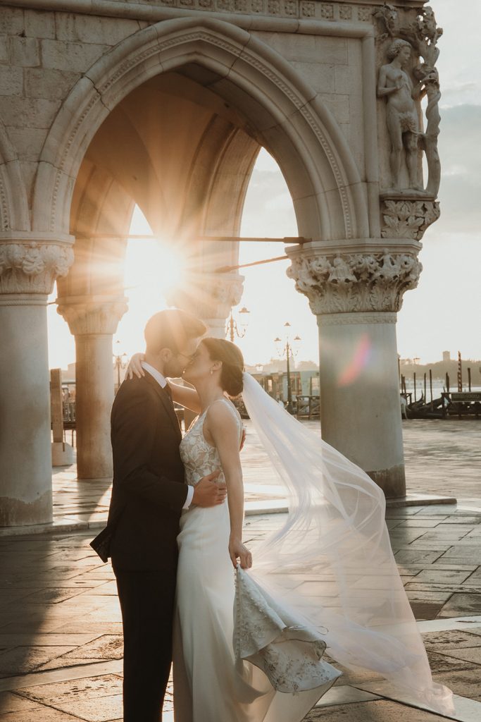 Bride and groom kissing candidly on their elopement in Venice as the sun rises on Palazzo Ducale