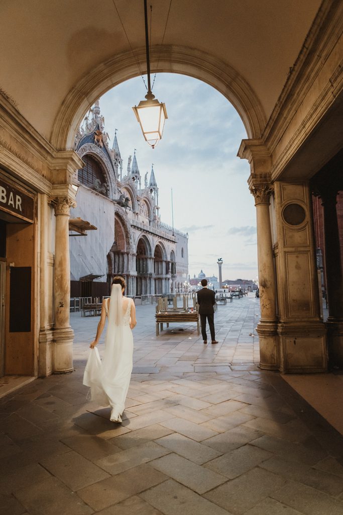 Bride and groom walking towards their first look spot right before sunrise on their elopement in Venice