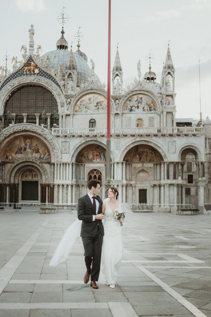 Bride and groom walking happily through an empty Piazza San Marco during their Venice elopement