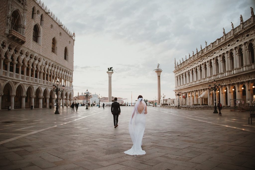 Bride and groom walking towards their first look spot right before sunrise on their elopement in Venice