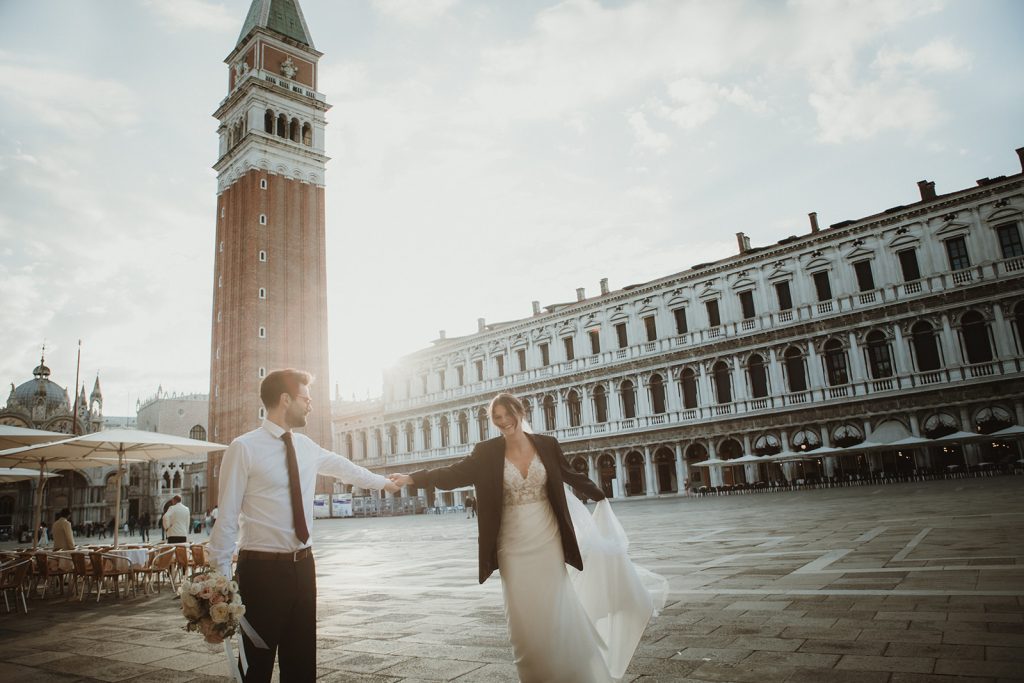 Couple dancing happily in Piazza San Marco as the first morning light hits the buildings