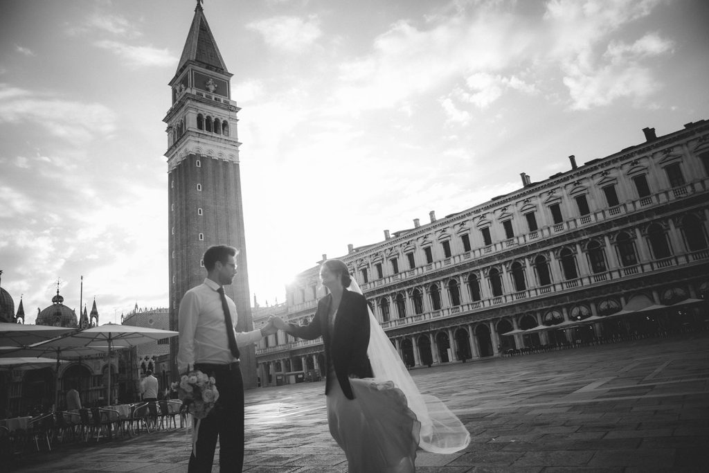 Couple dancing happily in Piazza San Marco as the first morning light hits the buildings