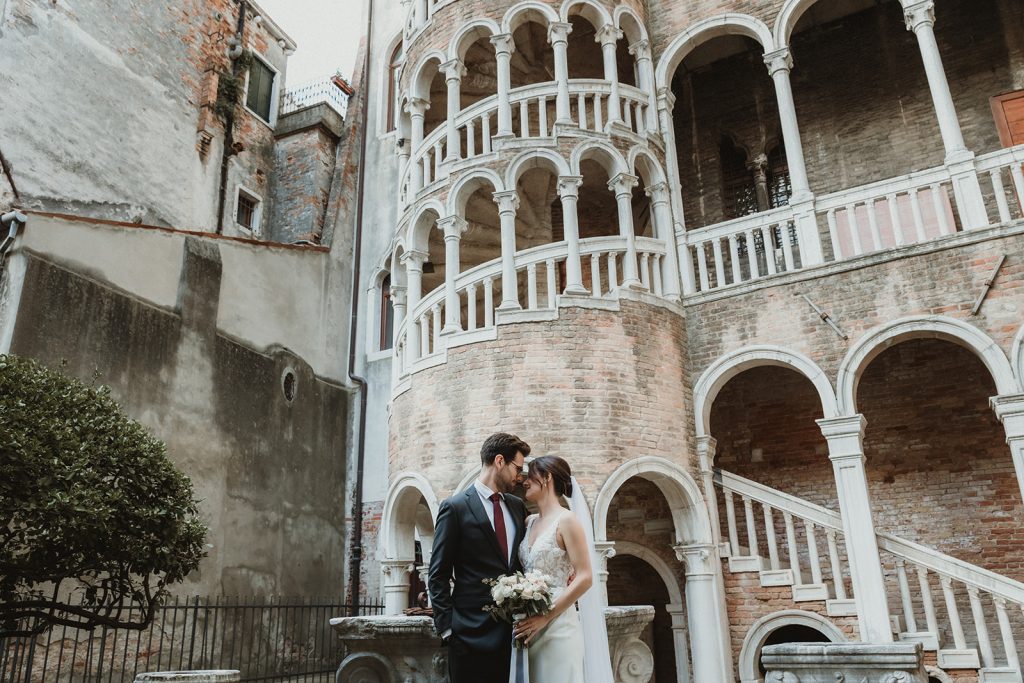 Couple kissing in front of Palazzo Contarini del Bovolo right before their ceremony on their elopement in Venice