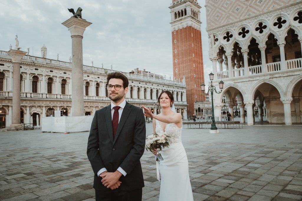 Bride about to touch groom's shoulder on their first look for their elopement in Venice