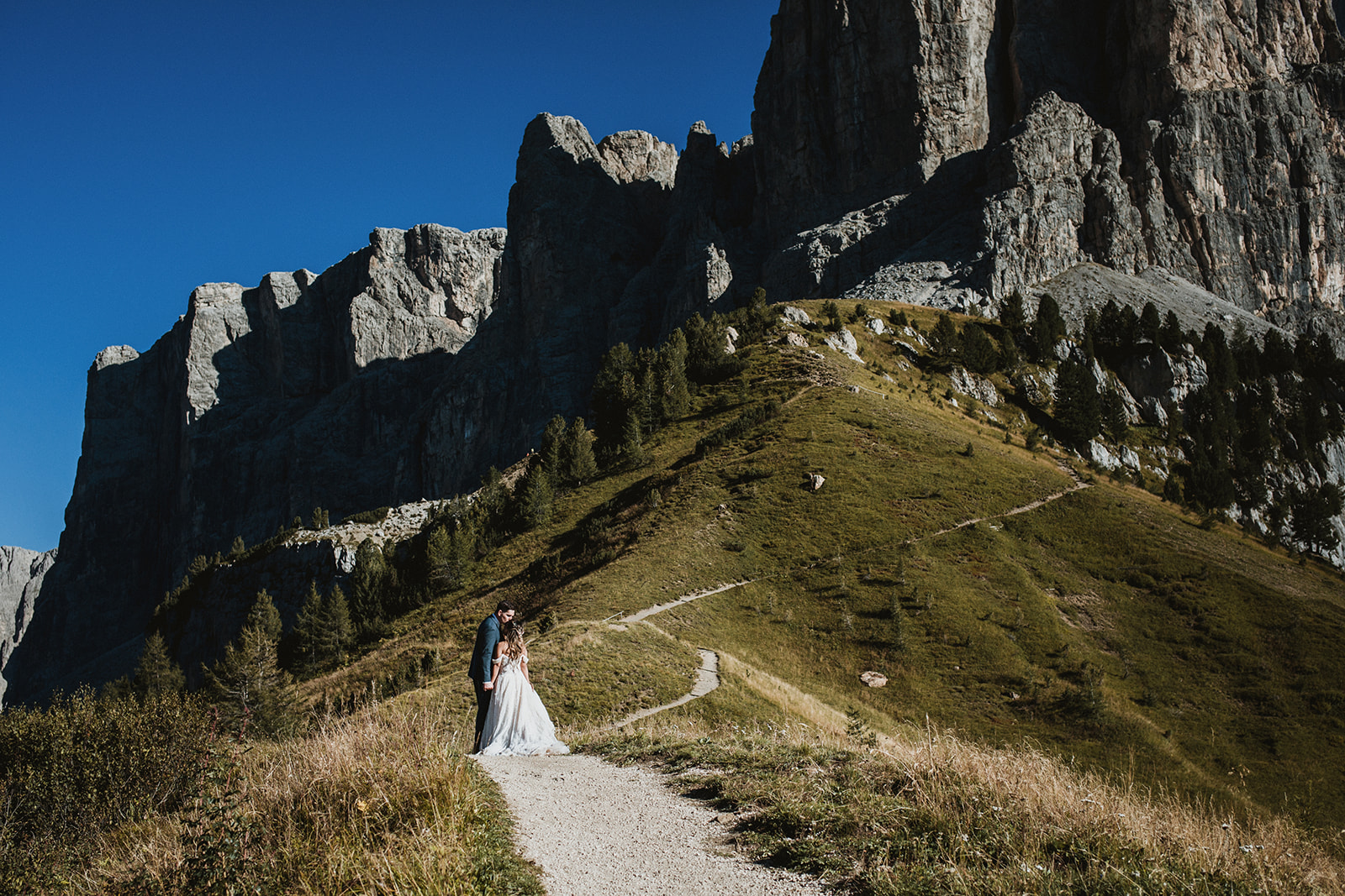 Couple gently walking on a mountain path at Passo Gardena on their Dolomites elopement