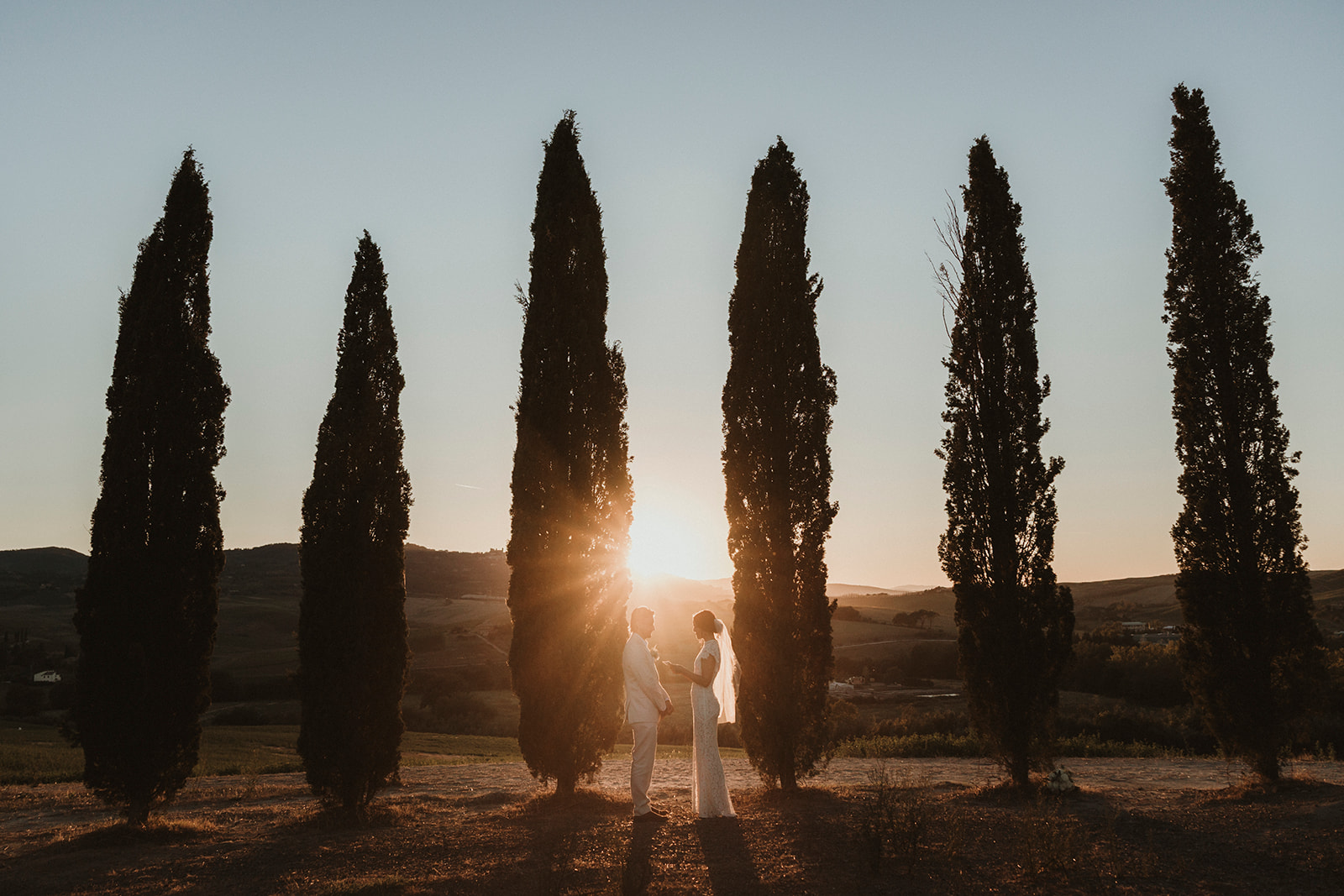 couple exchanging there vows surrounded by Tuscan cypresses with golden light