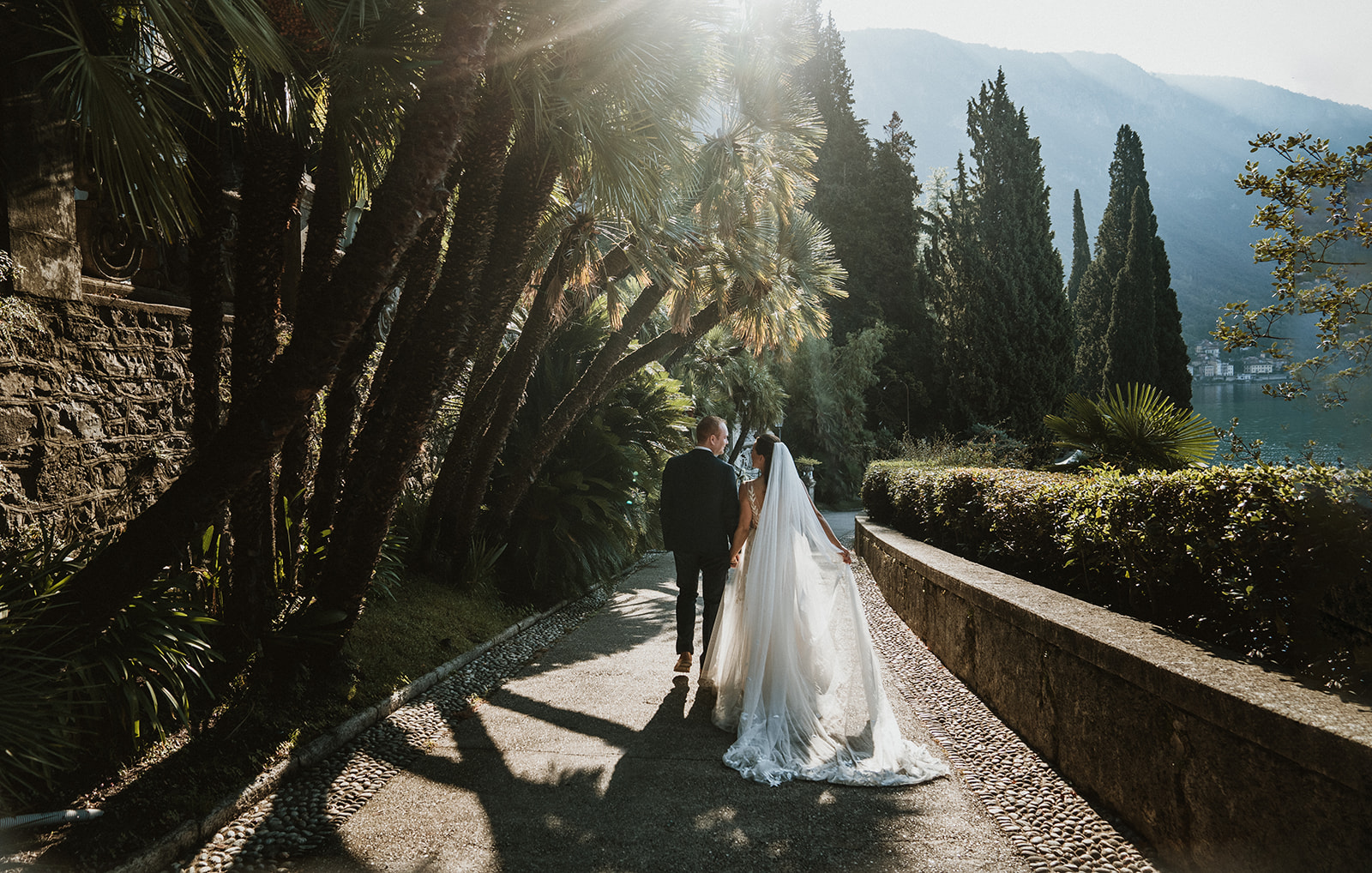 couple walking towards sunlight surrounded by lush gardens in Villa Monastero, Lake Como